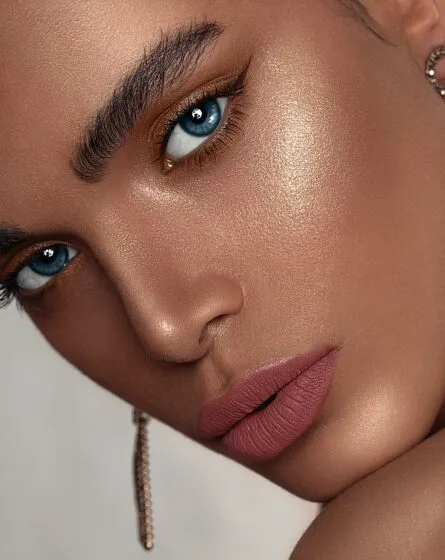 Mujer aplicando iluminador en el rostro, resaltando un look luminoso y natural con piel radiante.