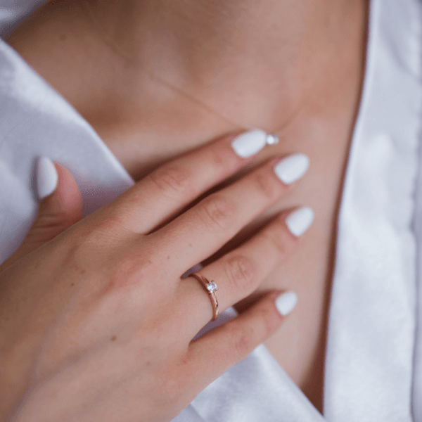 Primer plano de una mujer tocando el cuello y el escote con una mano con uñas cuidadas