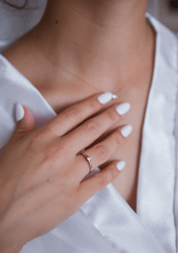 Primer plano de una mujer tocando el cuello y el escote con una mano con uñas cuidadas