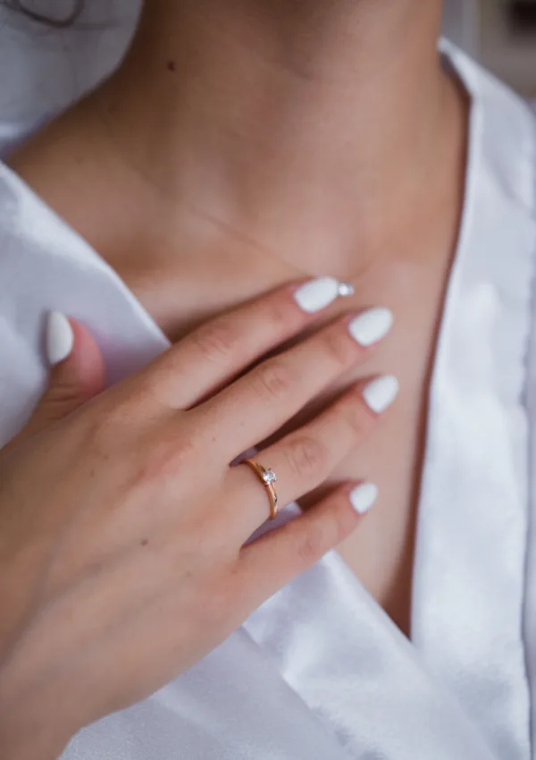 Primer plano de una mujer tocando el cuello y el escote con una mano con uñas cuidadas