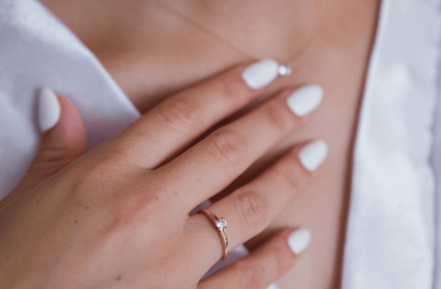 Primer plano de una mujer tocando el cuello y el escote con una mano con uñas cuidadas