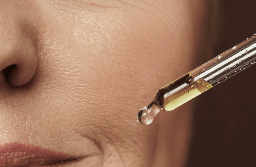 Mujer madura aplicando aceite facial con un gotero en su piel para hidratar y nutrir el rostro.