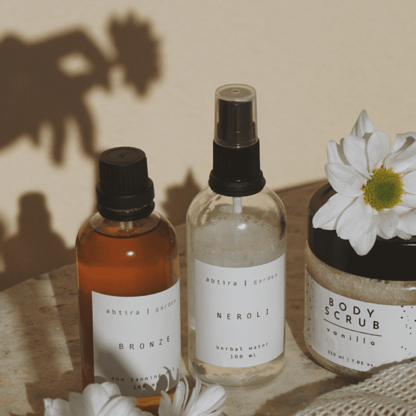 Aceite corporal o crema hidratante. Productos cosméticos naturales con flores sobre fondo neutro