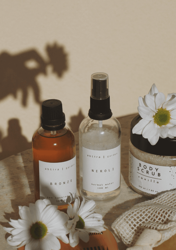 Aceite corporal o crema hidratante. Productos cosméticos naturales con flores sobre fondo neutro