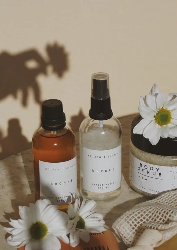 Aceite corporal o crema hidratante. Productos cosméticos naturales con flores sobre fondo neutro