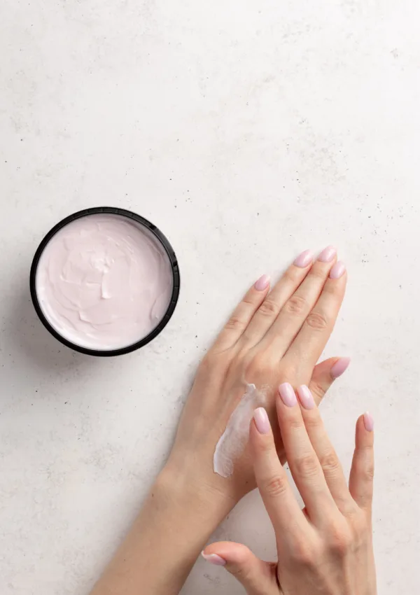 Hidratar manos muy secas. Aplicación de crema hidratante en manos secas con fondo blanco