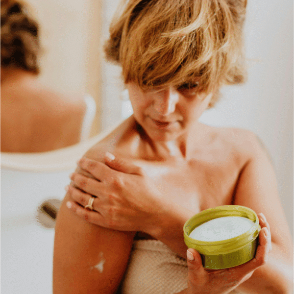 Los mejores after sun. Mujer aplicando crema after sun en los hombros tras la exposición solar