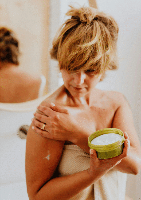 Los mejores after sun. Mujer aplicando crema after sun en los hombros tras la exposición solar