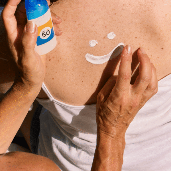 Protector solar mineral. Carita sonriente hecha con protector solar SPF 50 en la espalda de una persona.