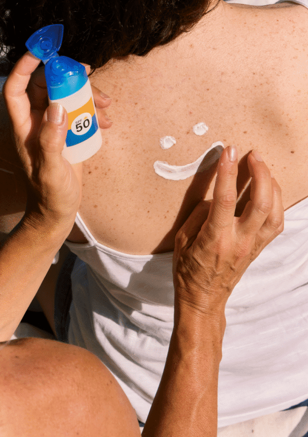 Protector solar mineral. Carita sonriente hecha con protector solar SPF 50 en la espalda de una persona.